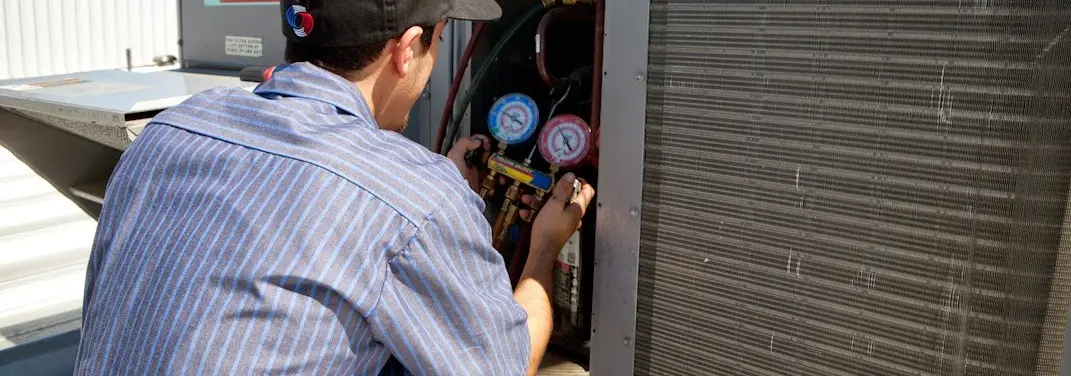 HVAC technician servicing a condenser unit in Mulvane